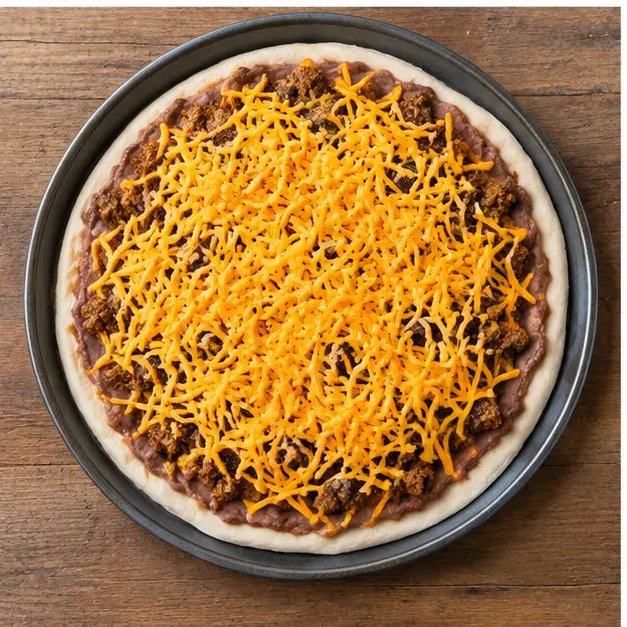 Step 3: layering refried beans, crumbled ground beef and shredded cheddar before baking